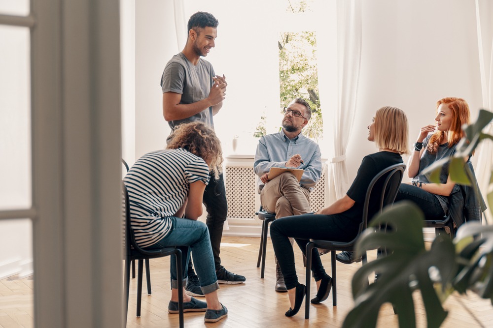 Happy hispanic man talking to his support group about his succes