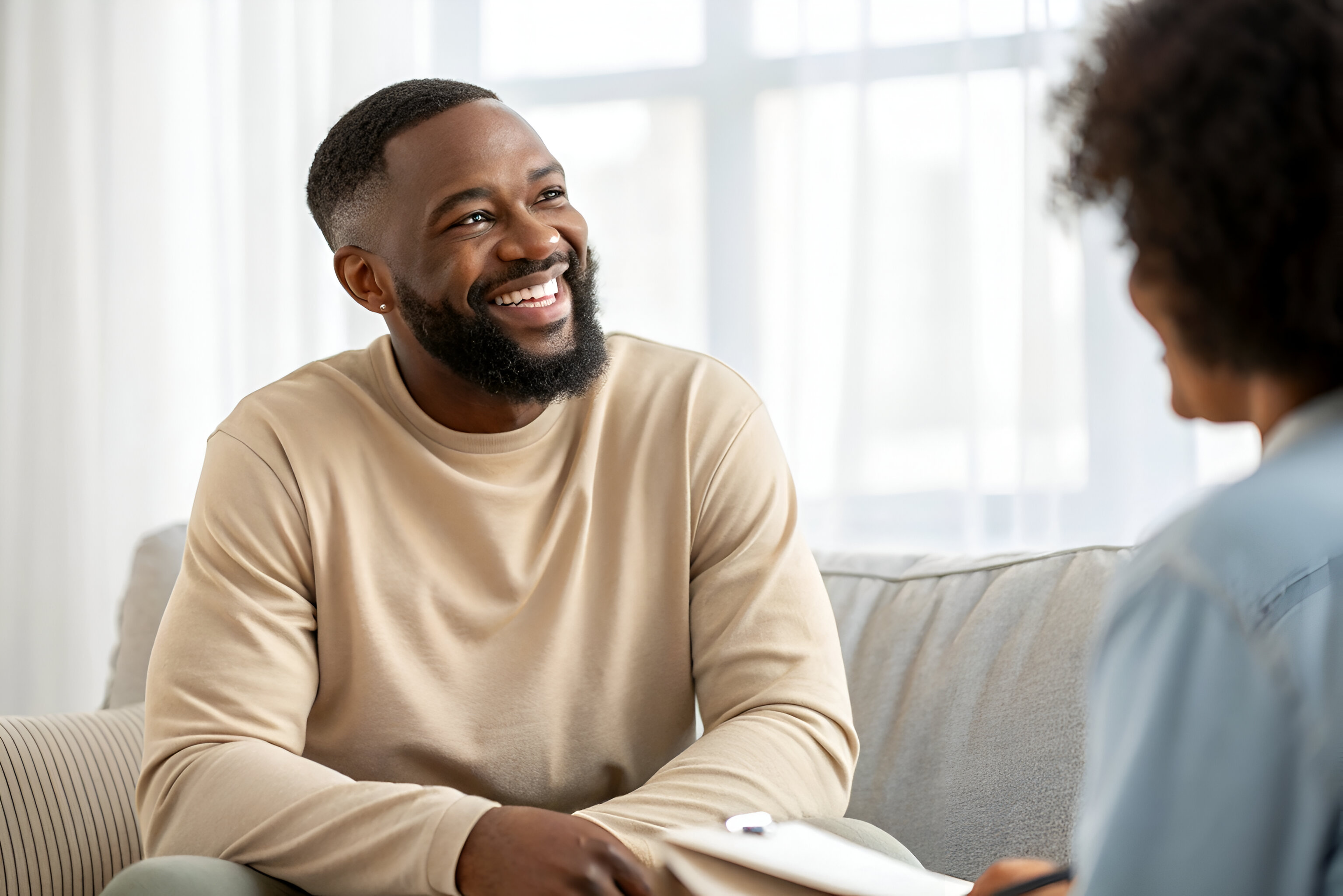 A Person And Another Person In A Therapy Session On A Couch in a Room Setting A picture of a middle aged man undergoing assessment for Opioid Recovery Program in Tennessee and Virginia.