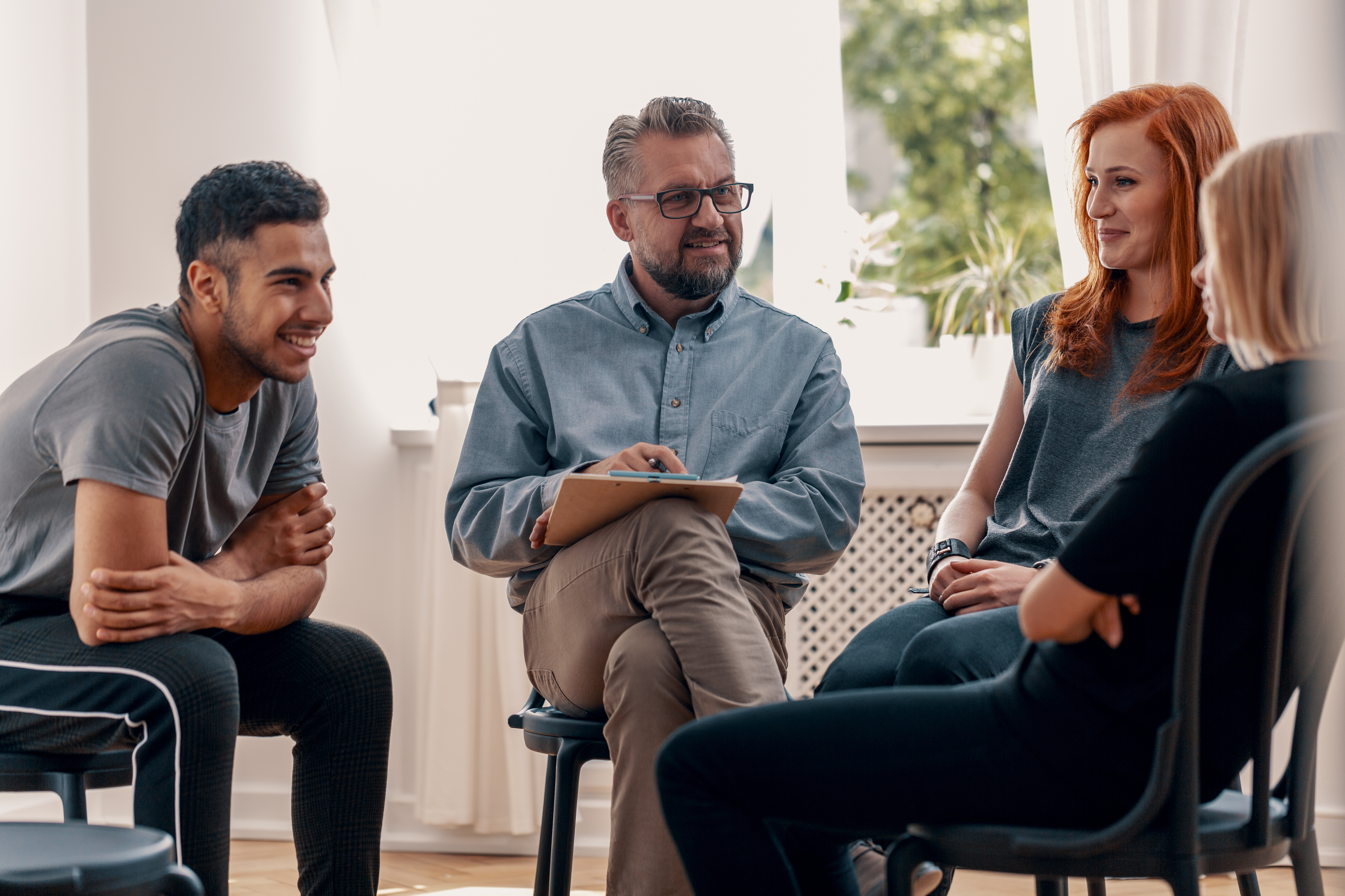 Smiling spanish man talking with friends during meeting for teen group of young individuals talking in Opioid Treatment Support Programs