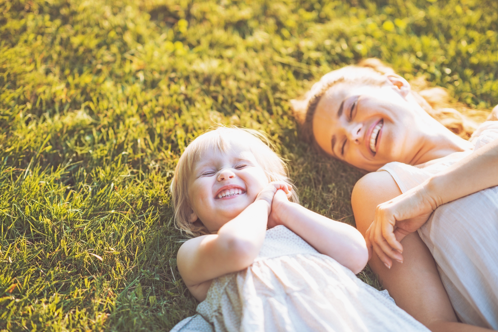 A happy mother and baby laying on meadow. Living a sober life after her methadone addiction treatment.